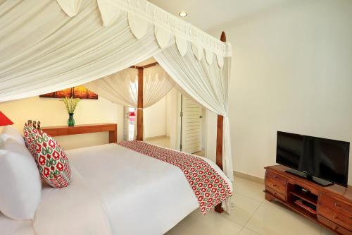 a bedroom with a white bed and a flat screen tv at Villa Lamac in Legian
