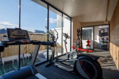 a gym with a treadmill and a room with windows at Chala Number 2 Art and Gallery in Chiang Mai