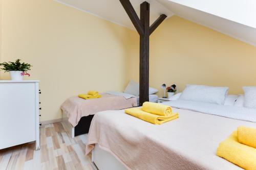 two beds in a room with yellow towels on them at Jane's Attic Apartment in Prague