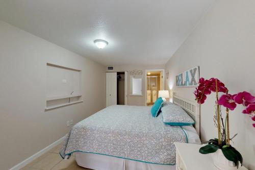 - une chambre avec un lit et un vase de fleurs dans l'établissement Solare Garden Villa 977, à South Padre Island