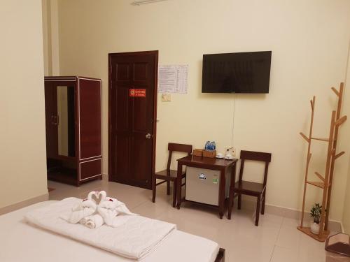 a room with a bed and a table and a television at Hostel Đặng Lợi ホステルダンロイ in Chau Doc