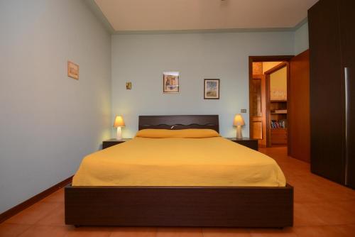 a bedroom with a large bed with yellow sheets at Casa vacanze con ampia piscina"Lago e Terme" in Sirmione