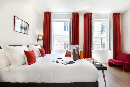 a bedroom with a large white bed with red curtains at Hotel Albert 1er in Toulouse