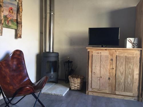a living room with a chair and a television and a wood stove at La Cabaña de Catalina in Sotres