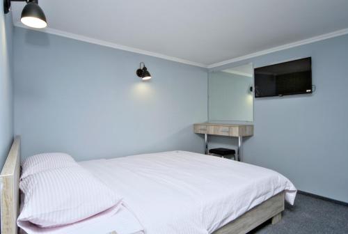 a bedroom with a white bed and a television at Grand Apartments in Kyiv