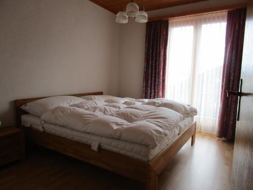 a bed in a room with a large window at Touring in Grächen