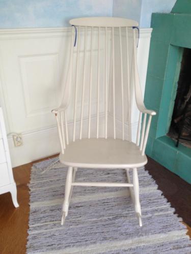 a white rocking chair in a room with a fireplace at Villa Verdi in Borgholm