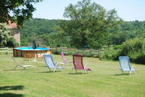 un groupe de chaises et une table dans l'herbe dans l'établissement Gite des Chambauds - Allier - Auvergne -12 pers, à Le Donjon