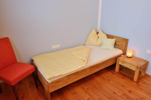 a bedroom with a bed and a red chair at Hildegard Naturhaus in Kirchberg bei Mattighofen
