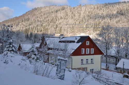 a red and white house in the snow at Apartmány pod Mariánskými schody in Albrechtice v Jizerských horách
