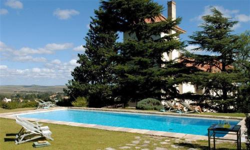 a swimming pool in front of a house with a tree at El Castillo de Mandl in La Cumbre