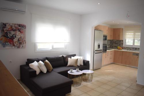 a living room with a black couch and a kitchen at Olive Sense Villa with jacuzzi and sauna in Afantou