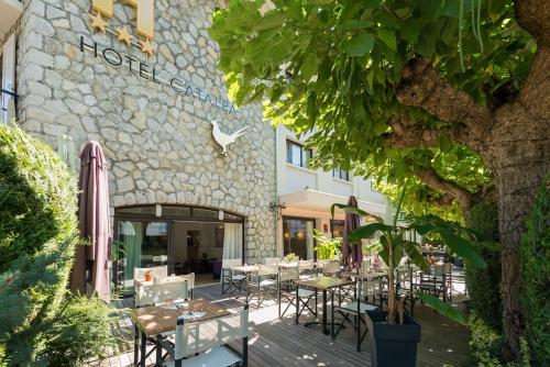 un restaurant avec des tables et des chaises en face d'un bâtiment dans l'établissement Hôtel Catalpa, à Annecy