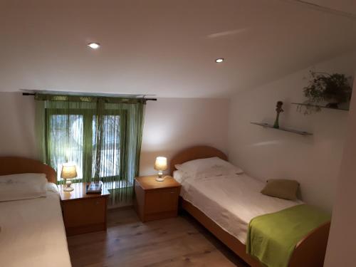 two beds in a room with two lamps and a window at Apartma Marisol in Izola