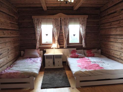 two beds in a room with two windows at Chata Mioduszyna w Beskidach - drewniany dom z widokiem na Babią Górę in Maków Podhalański