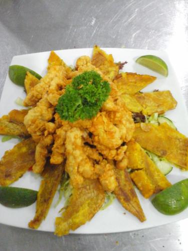a white plate of food with fried food and pickles at Hotel Campestre El Cisne in Barranquilla