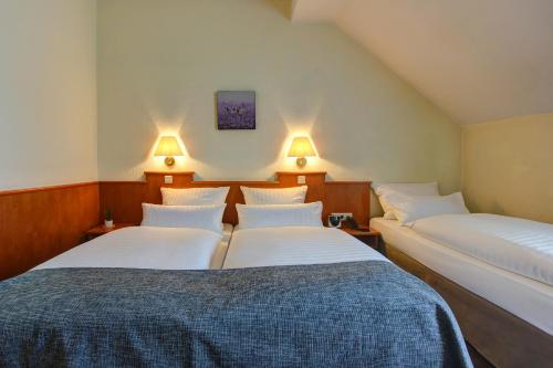 two beds in a room with two lamps on the wall at Sure Hotel by Best Western Ambassador Duesseldorf in Düsseldorf