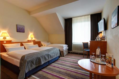 ein Hotelzimmer mit 2 Betten und einem Tisch in der Unterkunft Sure Hotel by Best Western Ambassador Duesseldorf in Düsseldorf