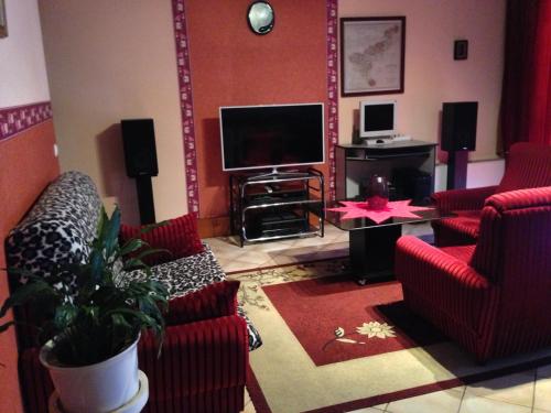 a living room with red chairs and a flat screen tv at Tommy Apartman in Hajdúszoboszló