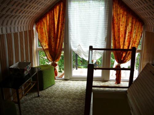 Habitación con ventana grande con cortinas de color naranja. en Cseresznyés Vendégház, en Mezőkövesd