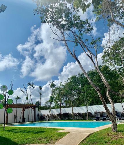 a swimming pool at a resort with a tree at Beautiful 3 BR/3.5 bath Home@Selvanova in Playa del Carmen