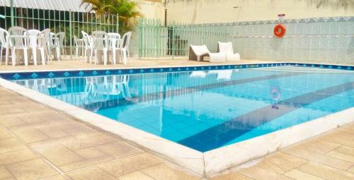 a swimming pool with white chairs and a blue at Hotel Cristo Rei 611 in São João del Rei