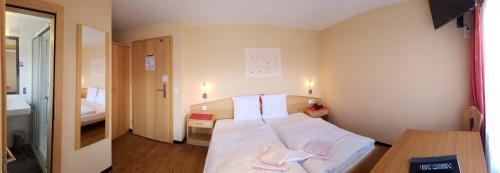 a hotel room with a bed and a desk and a room at Hotel Europa Guest House in Saas-Fee