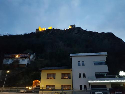 a building in front of a mountain at night at Le Merle Châtelain in Sion