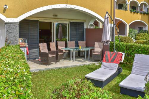 a patio with a table and chairs and an umbrella at Bed, boat and beach in Feriolo direkt am See in Baveno