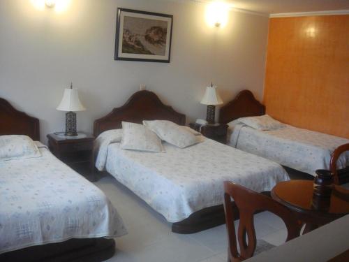 a hotel room with two beds and a table at HOTEL COSTA DEL SOL FUSAGASUGa in Fusagasuga