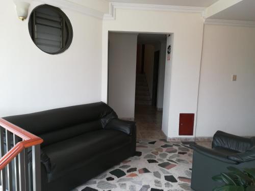 a living room with a black couch and a mirror at HOTEL COSTA DEL SOL FUSAGASUGa in Fusagasuga