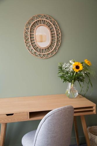 a table with a vase of flowers and a mirror at Le Patio in Yssingeaux
