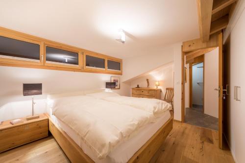1 dormitorio con 1 cama blanca grande y suelo de madera en Casa Alpetta en Flims