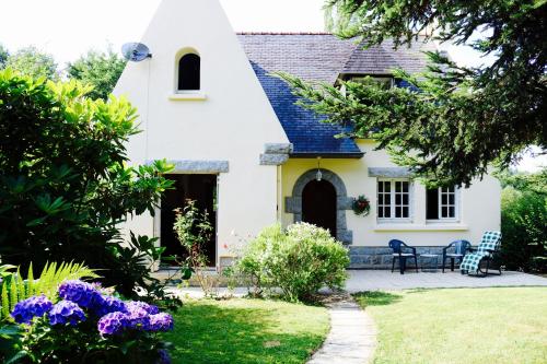 a white house with a yard with purple flowers at Fontaine Blanche River View, Large Patio & Garden in Central Brittany with Starlink WiFi in Treffrin