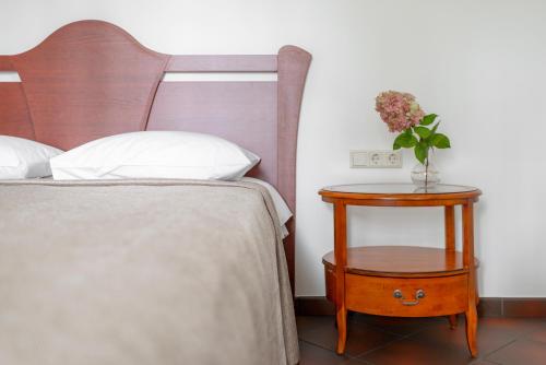 a bedroom with a bed and a nightstand with a vase of flowers at BURMISTRO NAMAS in Druskininkai