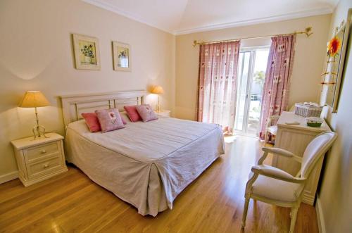 um quarto com uma cama com almofadas cor-de-rosa e uma cadeira em Apartamento Jarro em Quinta do Lago