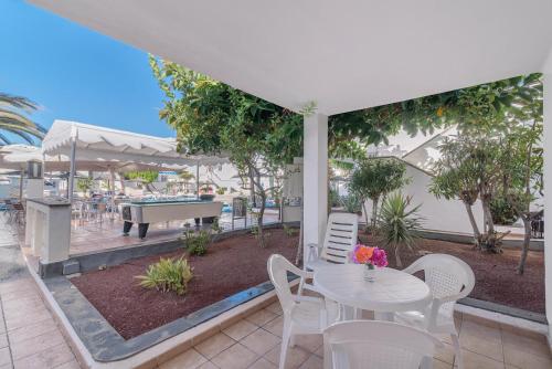 a patio with a table and chairs and a pool at Apartamentos Parque Tropical en Lanzarote in Puerto del Carmen