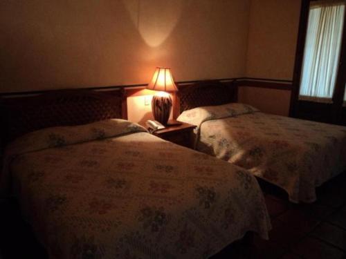 a bedroom with two beds and a lamp on a night stand at Hotel Hacienda Cazadores in Navojoa