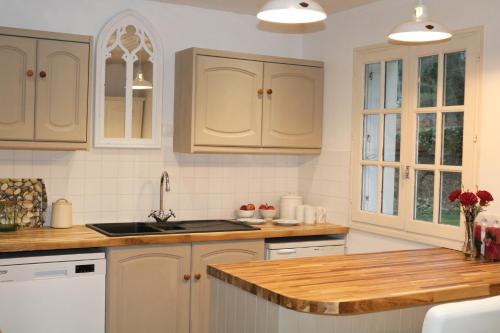 a kitchen with white cabinets and a sink at Fontaine Blanche River View, Large Patio & Garden in Central Brittany with Starlink WiFi in Treffrin