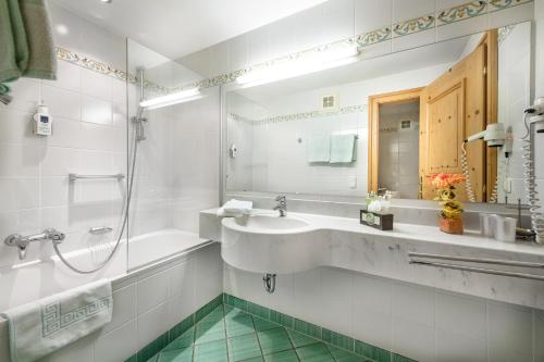 ein Badezimmer mit einem Waschbecken, einem Spiegel und einer Badewanne in der Unterkunft Villa St. Georg in Bad Hofgastein