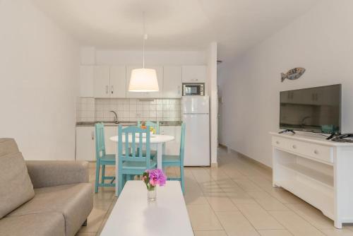 a living room with a couch and a table and a kitchen at Apartamentos Parque Tropical en Lanzarote in Puerto del Carmen