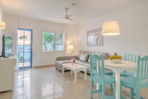 a living room with a couch and a table and chairs at Apartamentos Parque Tropical en Lanzarote in Puerto del Carmen
