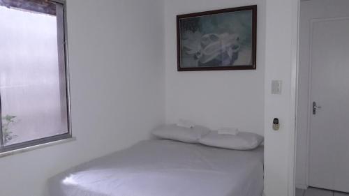 Habitación blanca con cama con una foto en la pared en BEACH HOUSE ARUANA, en Aracaju