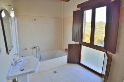 baño con bañera, lavabo y ventana en Maria Villas en Kíssamos