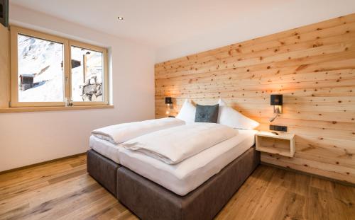 Cama en habitación con pared de madera en Bildegg Appartements, en Warth am Arlberg