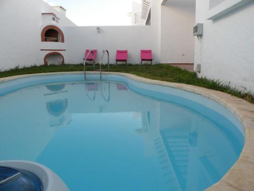 uma piscina com duas cadeiras cor-de-rosa ao lado de um edifício em Villa El Andalousse em Larache