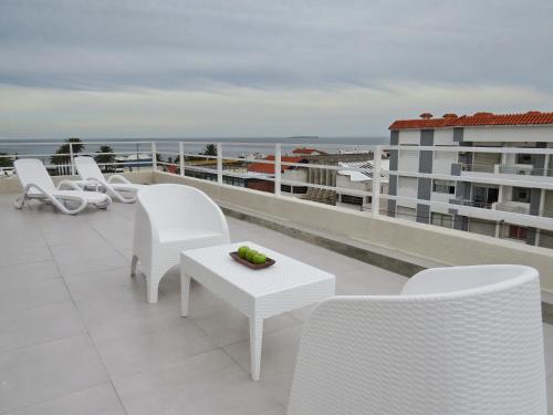 a balcony with white chairs and a table and the ocean at Atlántico Boutique Hotel in Punta del Este