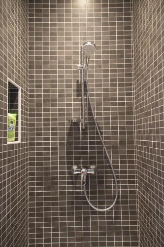 a shower in a bathroom with a tiled wall at La Mésange in Millau