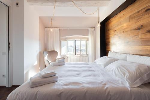 una camera da letto con un grande letto bianco con testiera in legno di Roommo Fortezza a Firenze