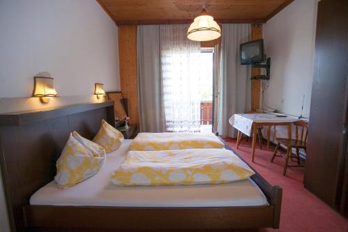Schlafzimmer mit einem Bett mit gelber und weißer Bettwäsche in der Unterkunft Ferienpension Garni Hubert Rigelnik in Sankt Kanzian am Klopeiner See